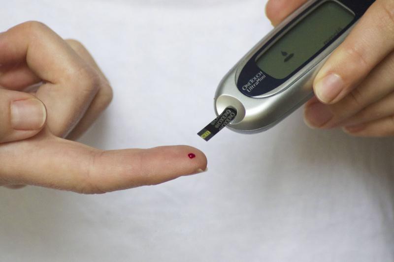 Medidor de glucosa en la sangre, pinchando la punta de su dedo con una lanceta